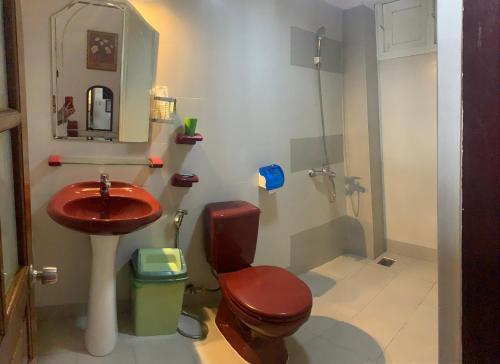baño con aseo rojo y lavamanos en Da Lat 24h Guesthouse & Hotel, en Da Lat