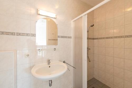 La salle de bains blanche est pourvue d'un lavabo et d'une douche. dans l'établissement Vakantiehuis BonBuren, à Buren