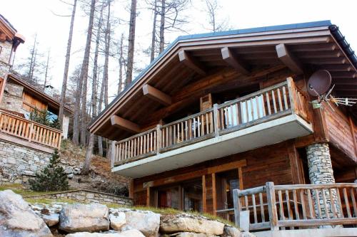 a log cabin with a balcony in the woods at Madame Vacances Chalet Acajuma in Le Joseray
