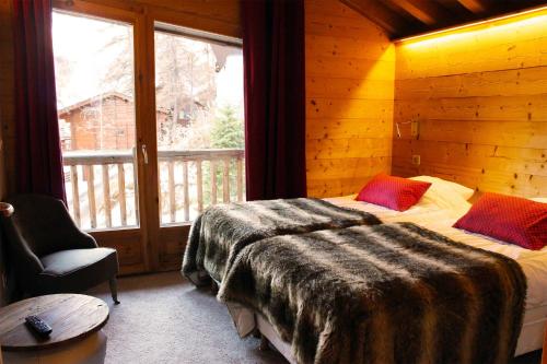 a bedroom with a bed and a large window at Madame Vacances Chalet Acajuma in Le Joseray