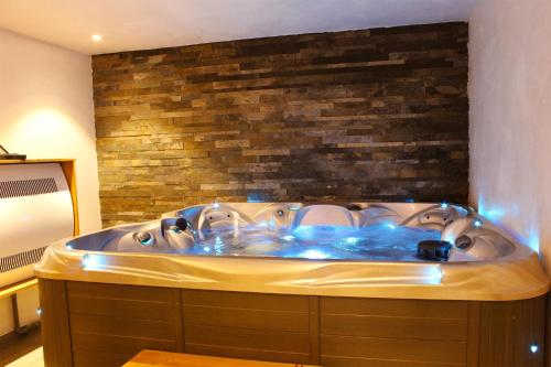 a large bath tub in a room with a brick wall at Madame Vacances Chalet Acajuma in Le Joseray