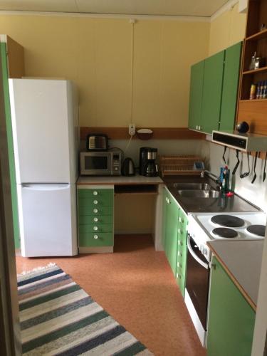 a kitchen with green cabinets and a white refrigerator at Å-hemmet i Dikanäs in Kittelfjäll