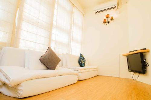 a living room with a white couch and a tv at SSS Life Hotel in Tainan