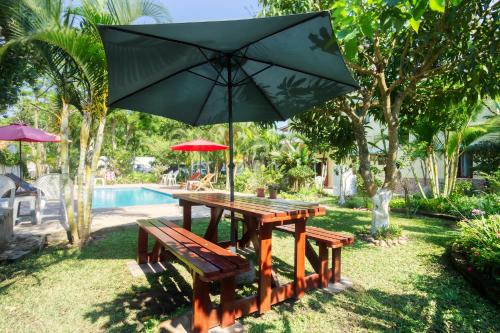 a picnic table with an umbrella next to a pool at Ilha Azul House in Ponta do Ouro