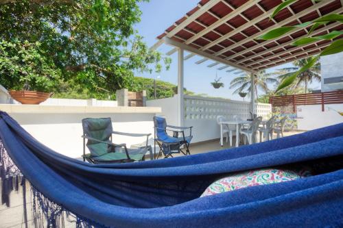 a hammock on a patio with chairs and a table at Ilha Azul House in Ponta do Ouro