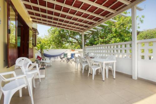 a patio with white chairs and tables on a porch at Ilha Azul House in Ponta do Ouro
