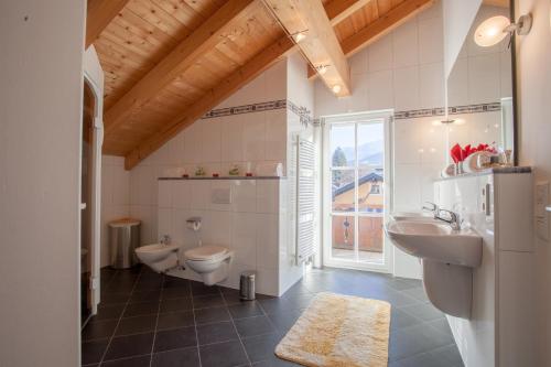 ガルミッシュ・パルテンキルヒェンにあるAlpenblickのバスルーム(洗面台2台、トイレ付)、窓が備わります。