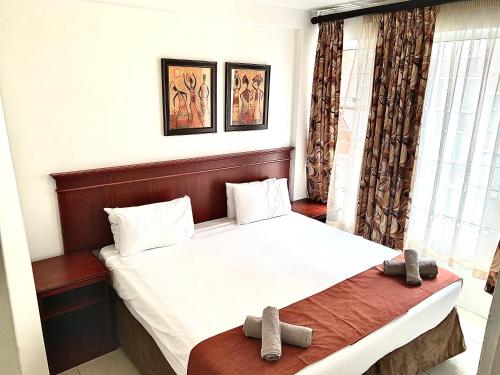 a bedroom with a bed with two slippers on it at Emakhosini Self-Catering Apartments in Durban