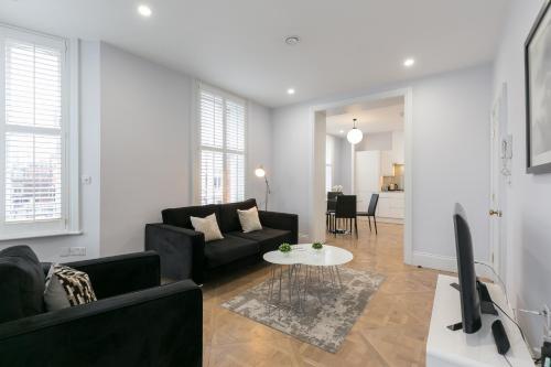 a living room with a black couch and a table at Urban Chic - Shaftesbury in London