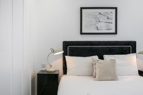 a bedroom with a white bed with a black headboard at Urban Chic - Shaftesbury in London