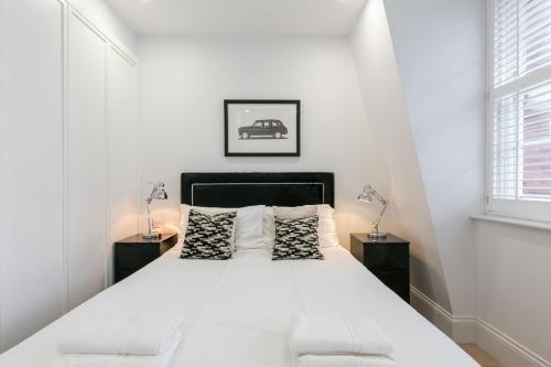 a white bedroom with a large bed with two night stands at Urban Chic - Shaftesbury in London