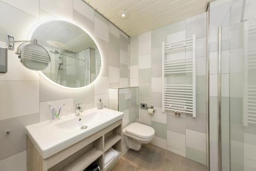 een badkamer met een wastafel, een toilet en een spiegel bij Hotel Bispinger Heide by Center Parcs in Bispingen