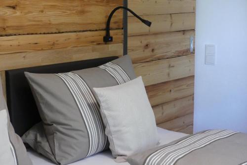 a bed with two pillows and a wooden wall at Ferienwohnungen Hasenknuck in Michelau
