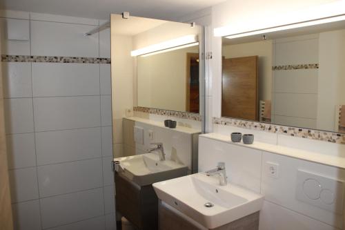 a bathroom with two sinks and two mirrors at Ferienwohnungen Hasenknuck in Michelau
