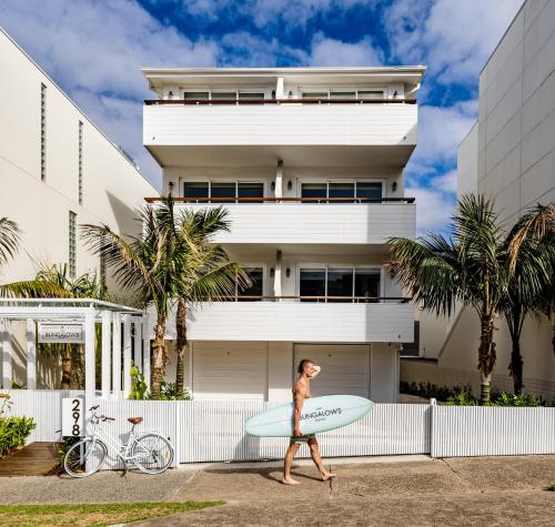 a person walking down the street with a surfboard at The Bungalows at Bondi in Sydney