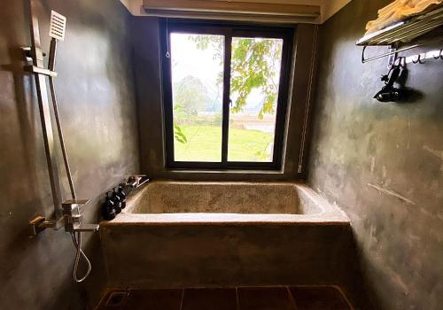 uma banheira na casa de banho com uma janela em Karst Villas Phong Nha em Phong Nha