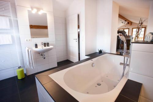 ein Badezimmer mit großer Badewanne und Waschbecken in der Unterkunft Auszeit Maisonette in Garmisch-Partenkirchen