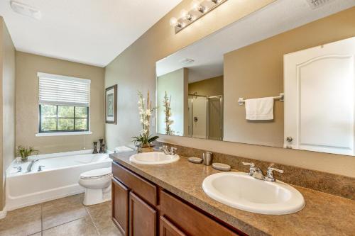 een badkamer met 2 wastafels, een bad en een toilet bij Cypress Pointe at Ellis Exclusive Villas in Davenport