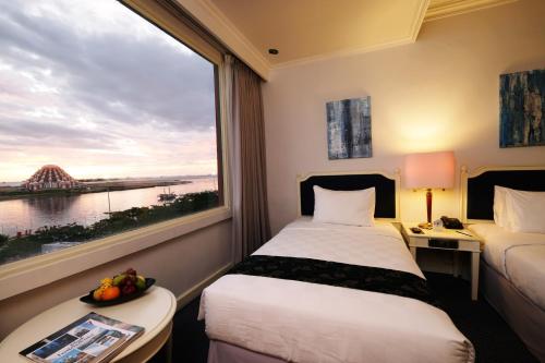 a hotel room with two beds and a large window at Aryaduta Makassar in Makassar