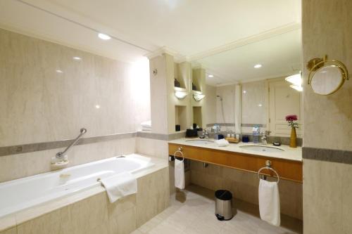 a bathroom with two sinks and a bath tub at Aryaduta Makassar in Makassar