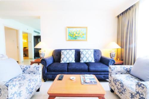a living room with a blue couch and two chairs at Aryaduta Makassar in Makassar