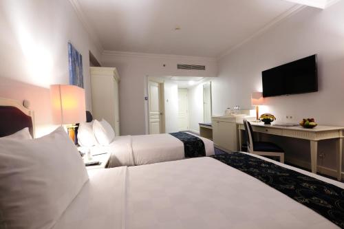 a hotel room with two beds and a desk at Aryaduta Makassar in Makassar