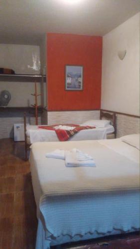 a bedroom with two beds and a red wall at Pousada Horto dos Contos in Ouro Preto