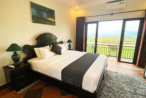 a bedroom with a large bed and a balcony at Karst Villas Phong Nha in Phong Nha