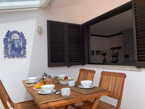 a wooden table with bowls and plates on it at FLH Cascais Charming Old Town in Cascais