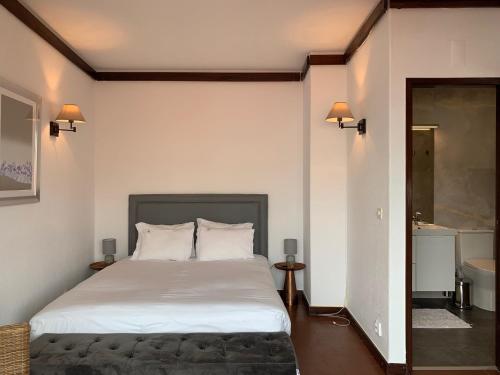 a bedroom with a large white bed and a bathroom at Charming old town in Cascais