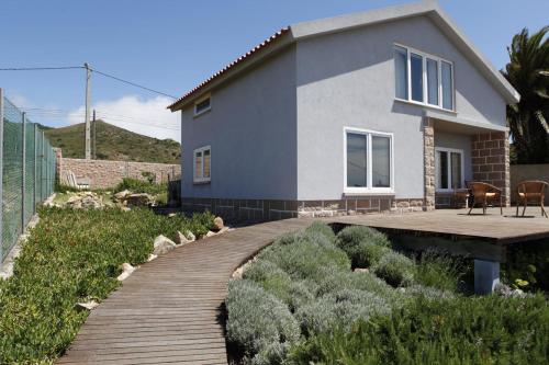 a house with a wooden walkway in front of it at FLH Mira Guincho House with Sea View and Garden in Alcabideche
