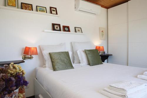 una camera bianca con un letto bianco e due lampade di Mira Guincho house with sea view and garden, Cascais a Alcabideche