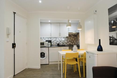 a kitchen with white cabinets and a table and yellow chairs at A piece of paradise in the heart of Cascais in Cascais