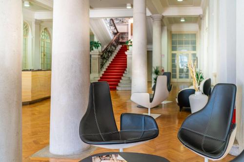 a lobby with four chairs and a staircase at Europalace Hotel, BW Signature Collection in Monfalcone