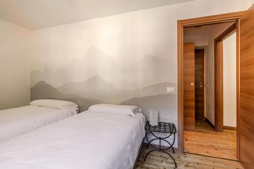 two beds in a room with a wall mural of mountains at Hotel Dufour in Macugnaga