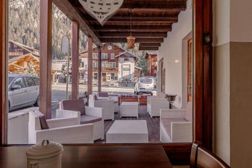 a room with white chairs and a view of a street at Hotel Dufour in Macugnaga