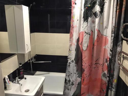 uma casa de banho com uma cortina de chuveiro com uma mulher em Астана 34 em Ustʼ-Kamenogorsk