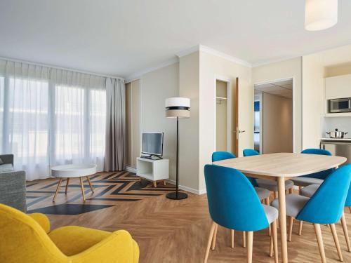 a living room with a dining room table and blue chairs at Aparthotel Adagio Porte de Versailles in Paris