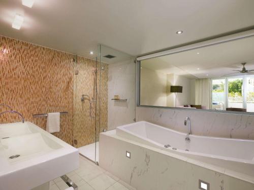 a bathroom with a tub and a sink and a mirror at Sofitel Noosa Pacific Resort in Noosa Heads