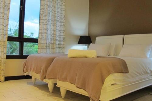 a bedroom with a large white bed and a window at Maison Bigorno by Simply-Seychelles in Eden Island