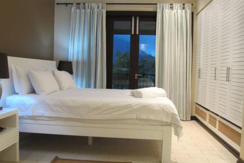 a bedroom with a white bed and a large window at Maison Bigorno by Simply-Seychelles in Eden Island