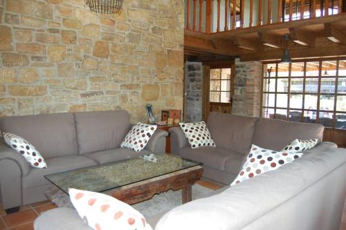 a living room with couches and a stone wall at Casa Rural El Entamáu in Argüero