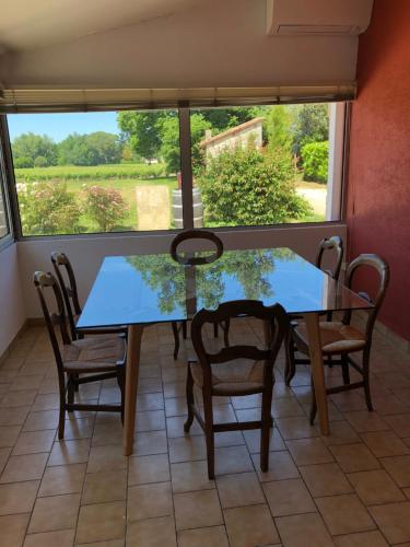 een eetkamer met een tafel en stoelen en een raam bij l'Orangerie de La Pontête in Vayres