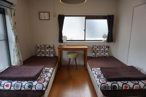 two beds in a room with a desk and a window at Guesthouse Ten-roku - Female Only in Osaka