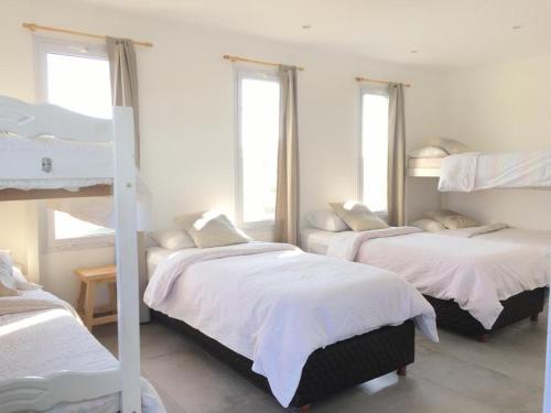 a bedroom with three bunk beds and two windows at Hostel de campo La Providencia in Lobos