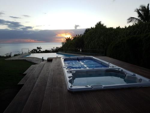a hot tub sitting on a deck next to the water at Chambre d'hotes "Villa Rayon Vert" in Deshaies
