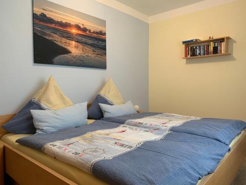 Una cama con sábanas azules y almohadas en un dormitorio en Haus Nordland en Langeoog
