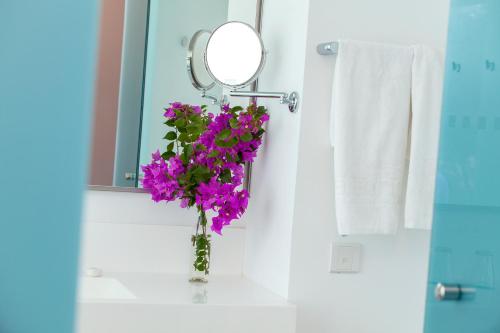 a vase of purple flowers in a bathroom at Aliathon Aegean in Paphos City