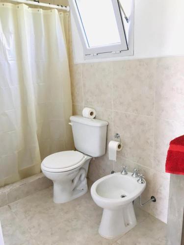 a bathroom with a toilet and a sink and a window at Hostel de campo La Providencia in Lobos