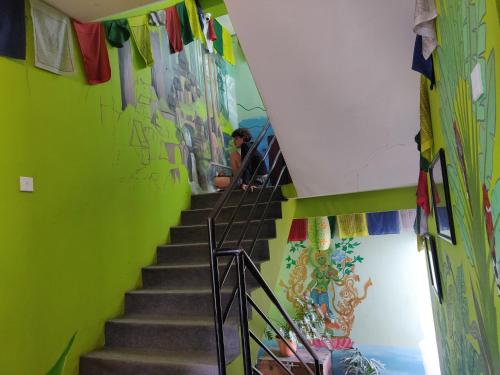 a staircase with a green wall and a person sitting on it at Yog Hostel- Rooftop Yoga & Backpacker Social Stay in Thamel, Kathamndu in Kathmandu